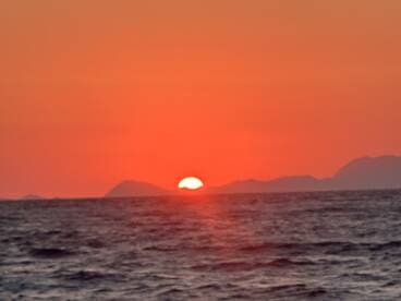 A stunning sunset over the ocean, casting vibrant hues across the sky and water — a perfect backdrop for evening boat cruises.