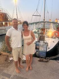 A happy couple poses at the dock next to their yacht, capturing a moment of celebration — perfect for romantic getaways or private yacht trips.