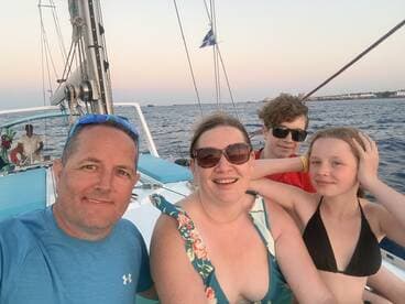 A joyful family captures a moment aboard a sailboat during sunset, creating lasting memories on the water.