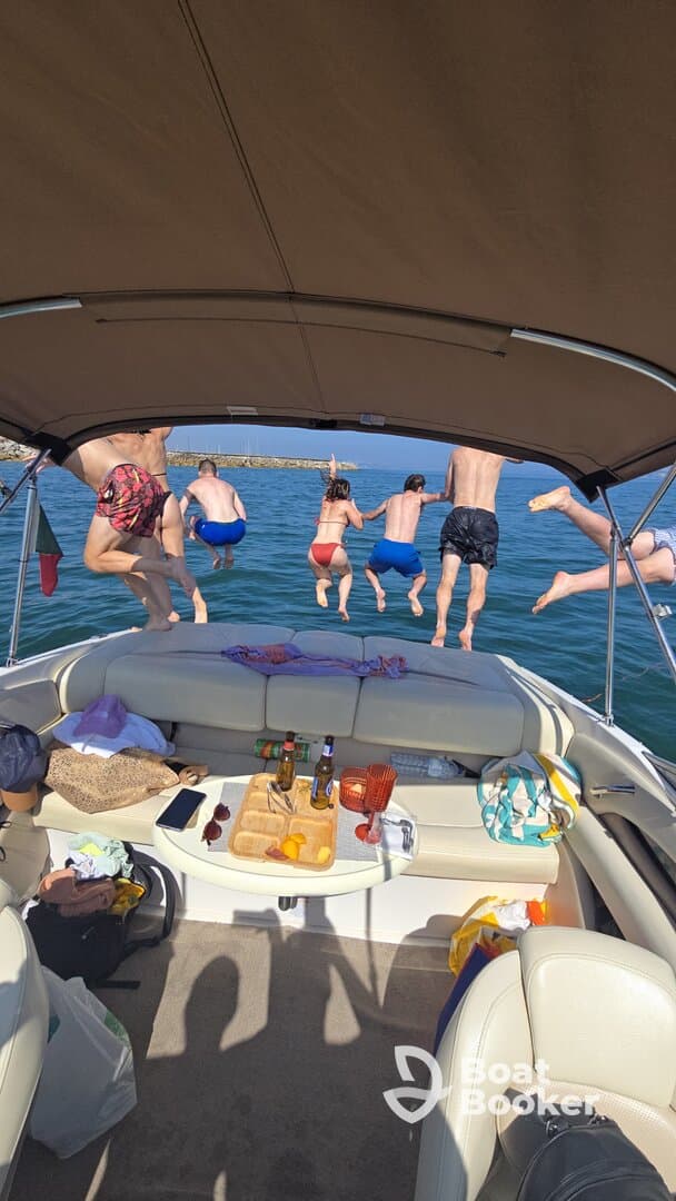 A lively group jumps into the water from the boat, capturing the essence of summer fun and adventure on the water.
