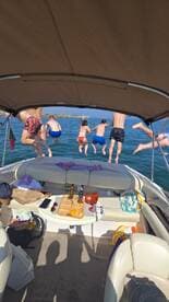 A lively group jumps into the water from the boat, capturing the essence of summer fun and adventure on the water.