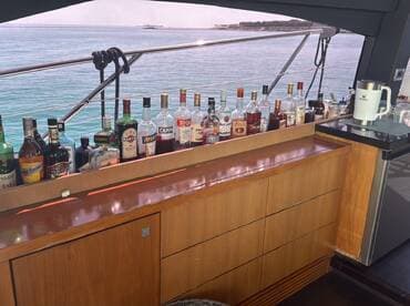 A well-stocked bar on a yacht featuring a variety of spirits, perfect for crafting cocktails while enjoying the scenic ocean views.