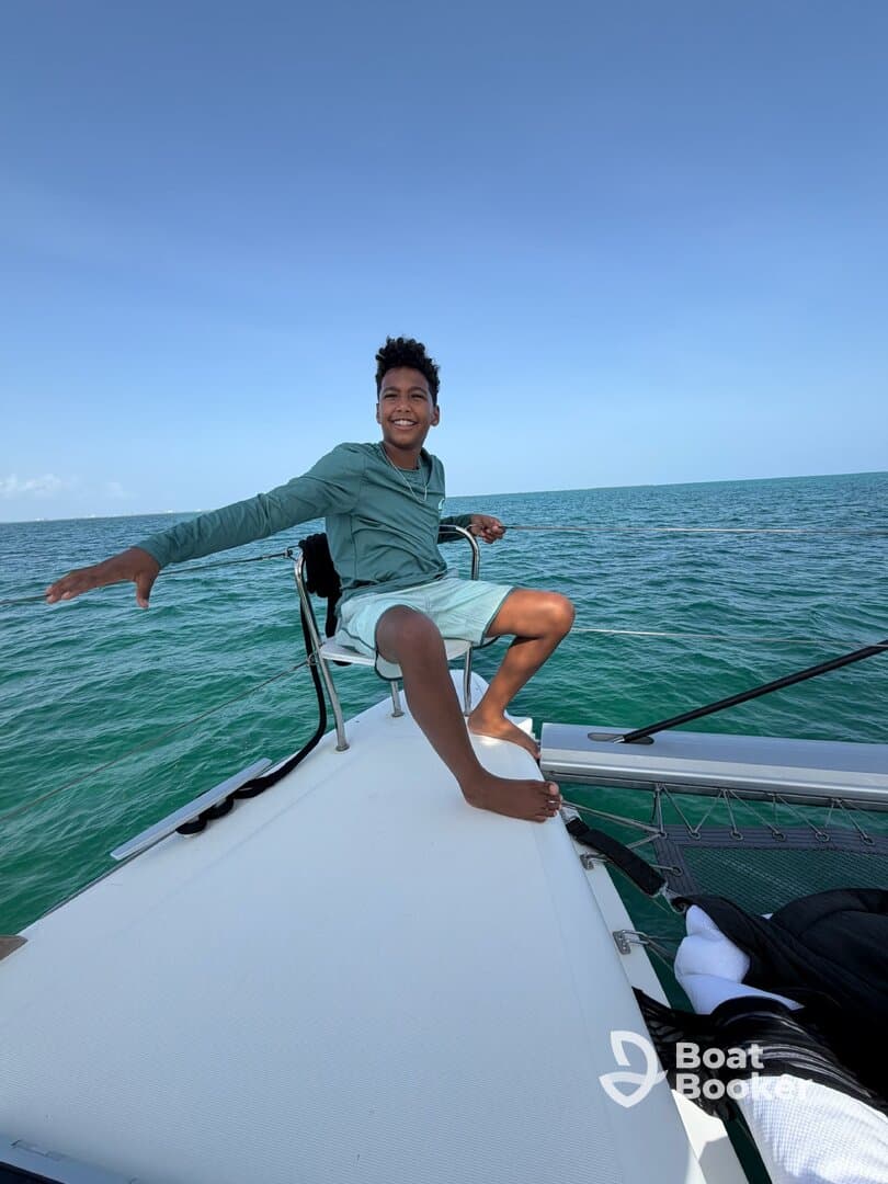A joyful boy enjoys a sunny day sailing on a boat, capturing the essence of fun and adventure on the water.