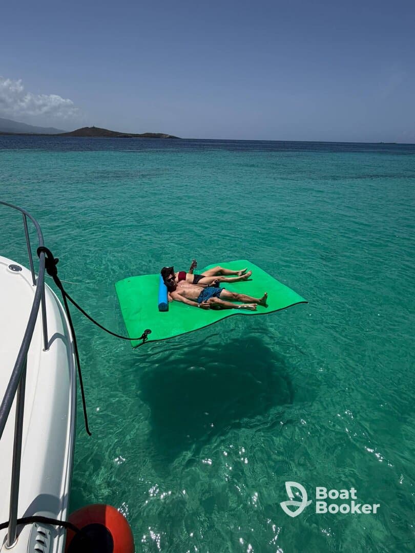 A couple relaxes on a floating mat in the stunning turquoise waters, enjoying a perfect day under the sun — an ideal scene for summer getaways.