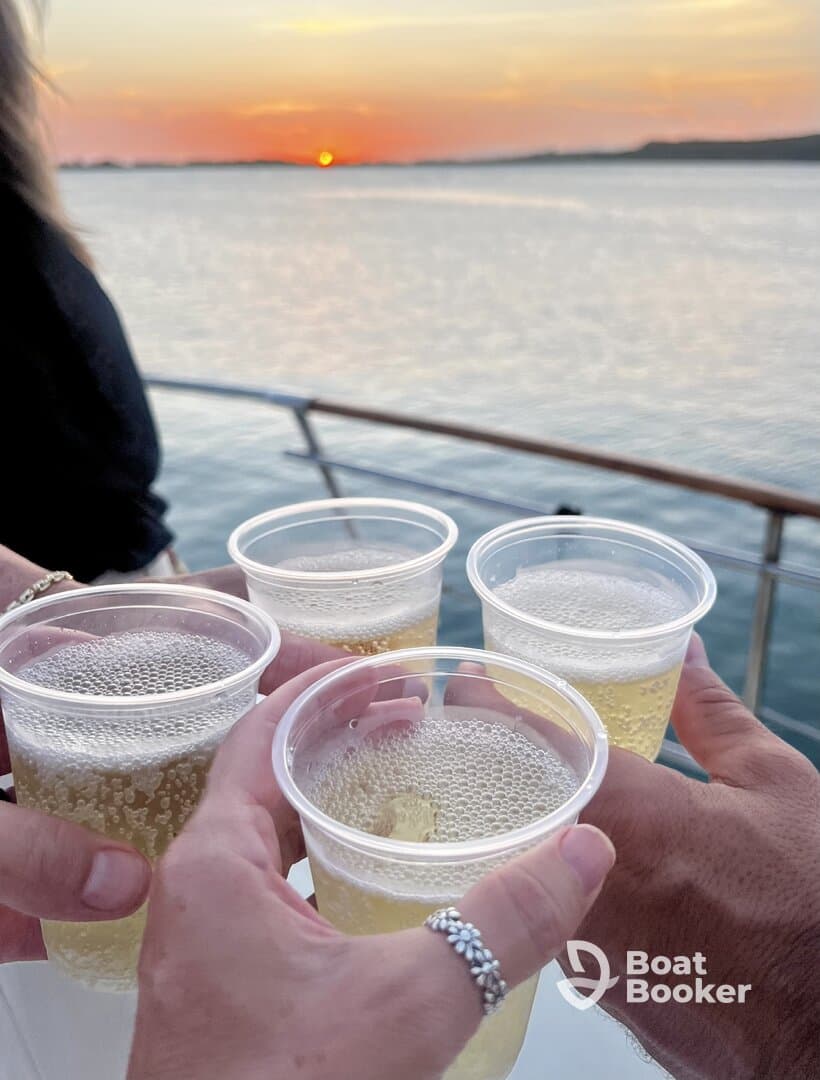 A group toasts with drinks against a stunning sunset backdrop, capturing the essence of celebration on the water.