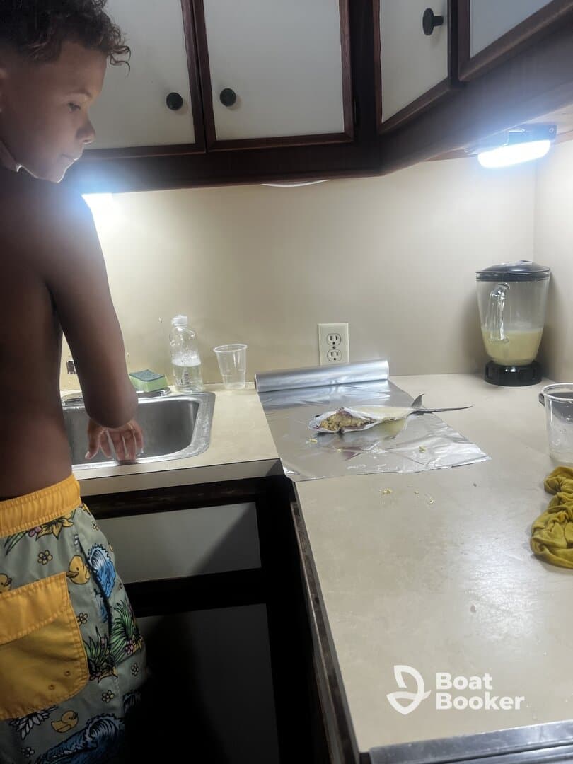 A young boy prepares freshly caught fish in the kitchen of a boat, showcasing the unique experience of cooking onboard.