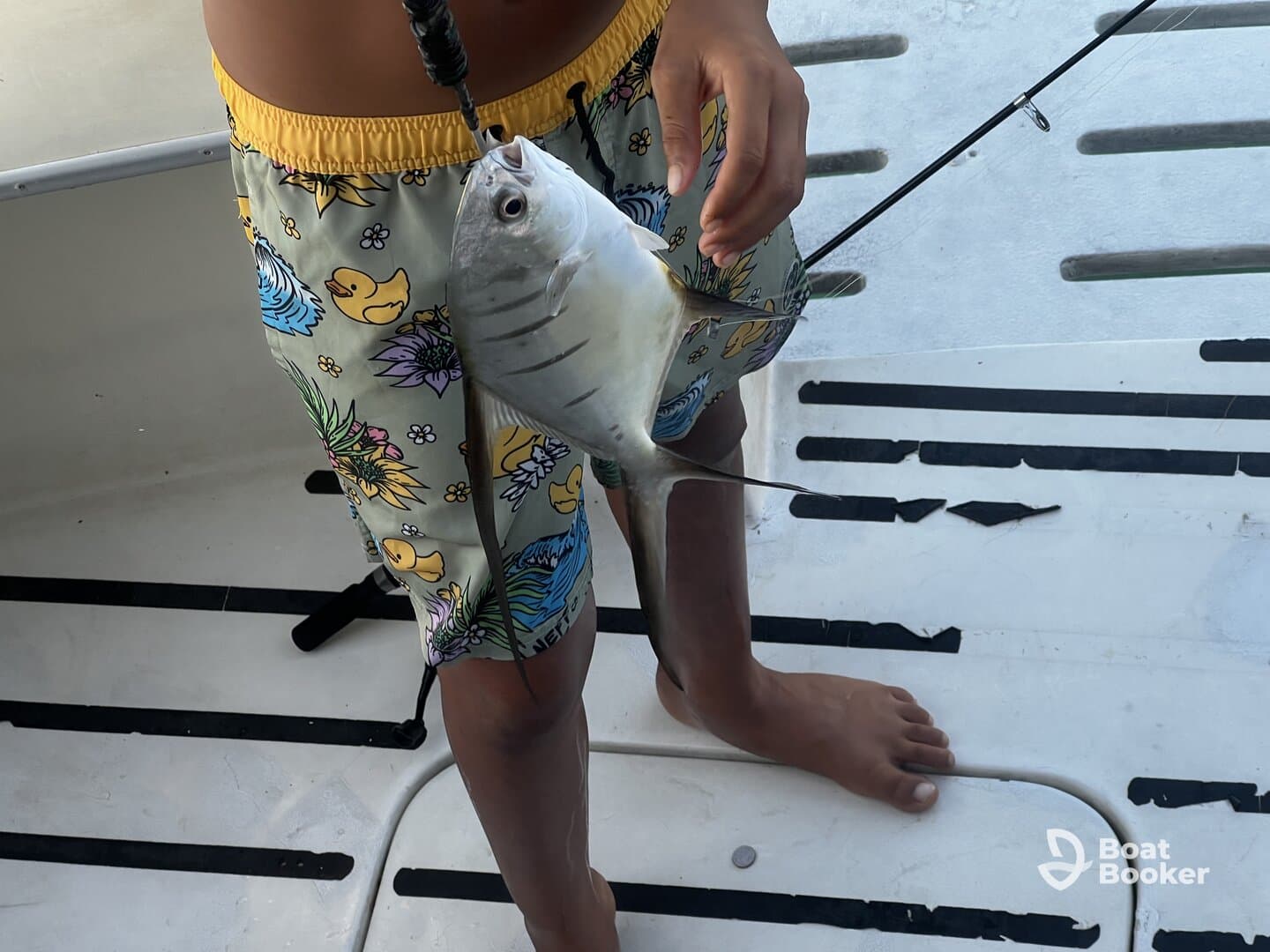 A child proudly holds up a freshly caught fish while standing on a boat, showcasing the excitement of a fishing adventure on the water.