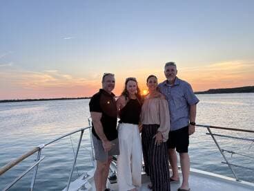 A group of friends poses for a photo on a boat at sunset, capturing a memorable moment during their cruise — perfect for celebrations and gatherings on the water.