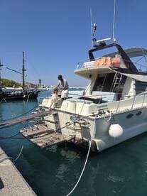 A father assists his daughter as they board a yacht at the dock, capturing a heartwarming family moment on the water.