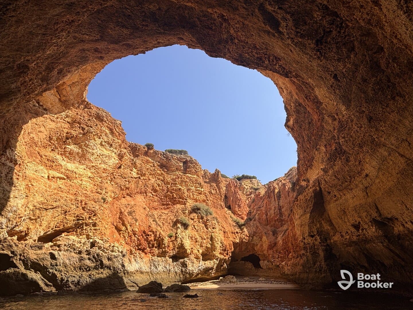 A stunning view of a natural cave formation, showcasing vibrant rock colors and clear blue skies — a perfect destination for scenic boat tours.