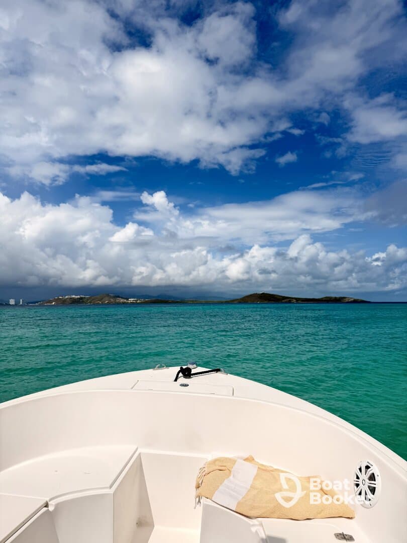 A serene view from the front of a boat cruising through turquoise waters, framed by a stunning sky and distant islands — perfect for a day of adventure on the water.