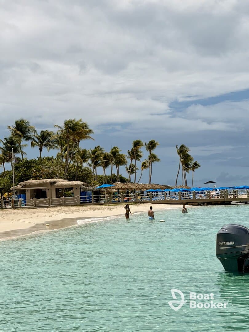 A group enjoys a sunny day at the beach, wading in the clear waters surrounded by palm trees — a perfect sandbar stop for relaxation and fun.