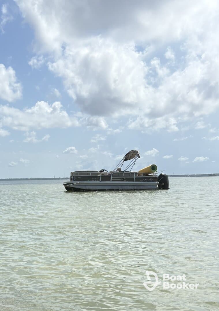 A serene view of a pontoon boat anchored in calm waters under a partly cloudy sky, perfect for leisurely outings on the water.