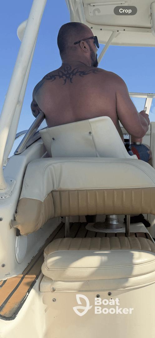 A view of the helm area inside a boat, featuring a man seated at the controls, showcasing the comfortable seating and layout for navigating the waters.