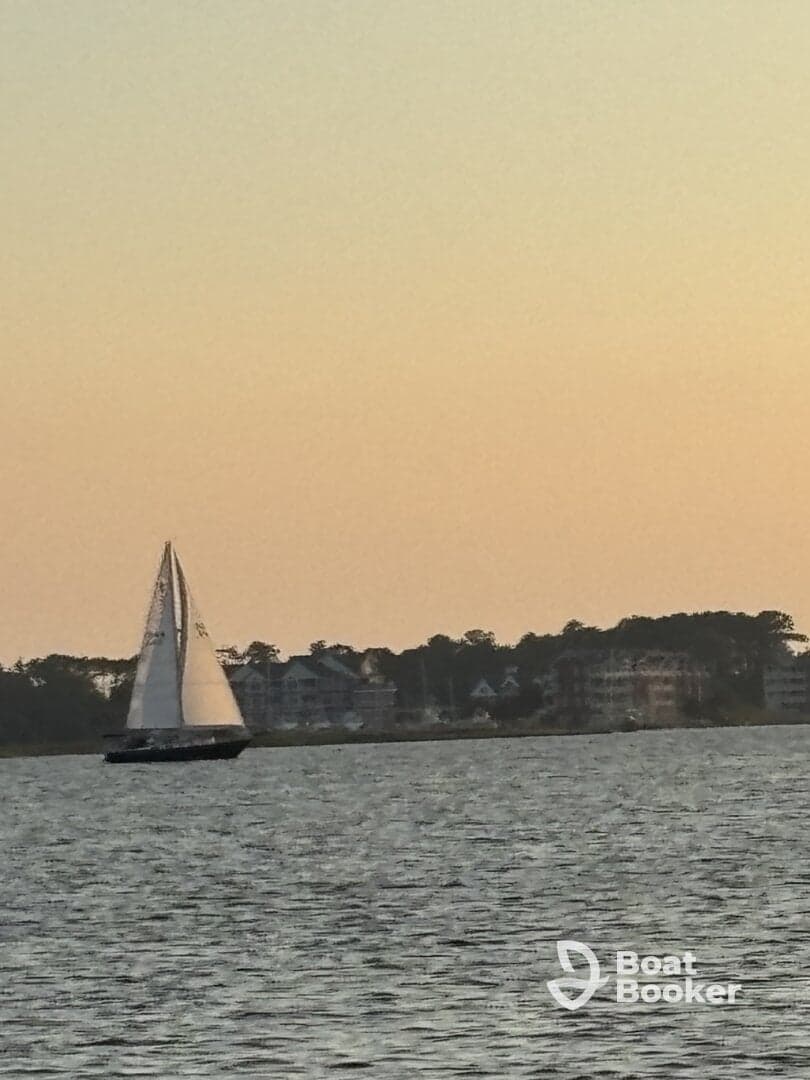 A serene view of a sailboat gliding across the water at sunset, showcasing the beauty of sailing and tranquil waterside scenery.