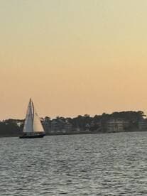 A serene view of a sailboat gliding across the water at sunset, showcasing the beauty of sailing and tranquil waterside scenery.