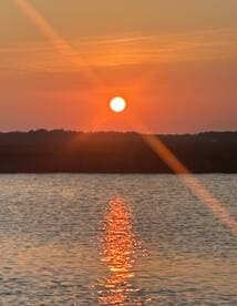 A stunning sunset casts a warm glow over the water, creating a beautiful reflection — perfect for capturing serene moments on the water.