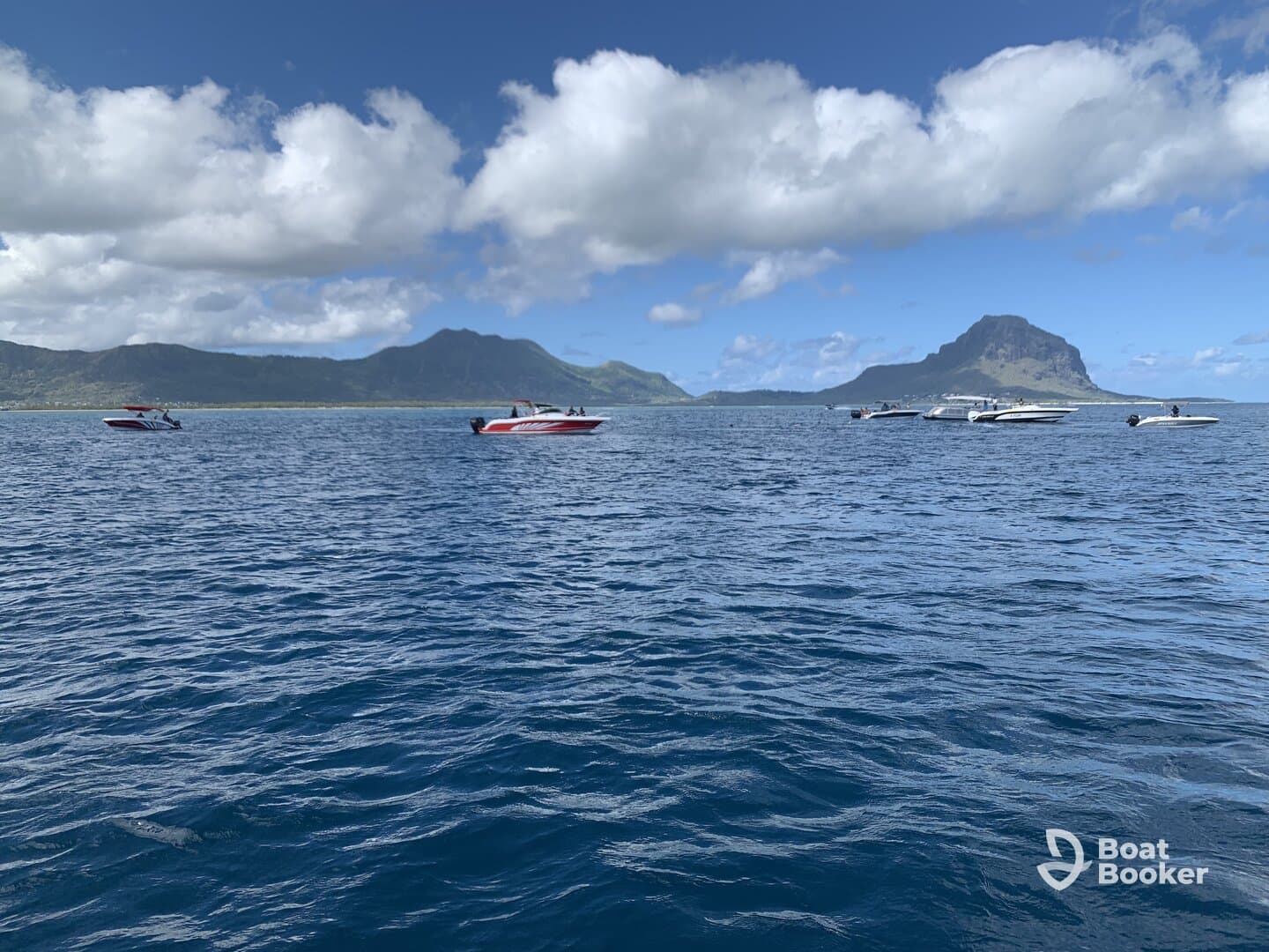 A picturesque view of several boats cruising near a stunning island backdrop, showcasing the beauty of the coastline and inviting adventure on the water.