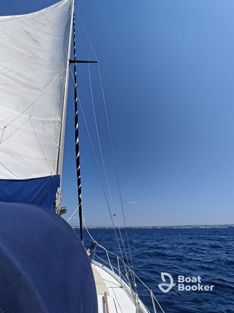 A close-up view of a sailboat's sail and deck as it navigates through clear blue waters, showcasing the beauty of sailing on the open sea.