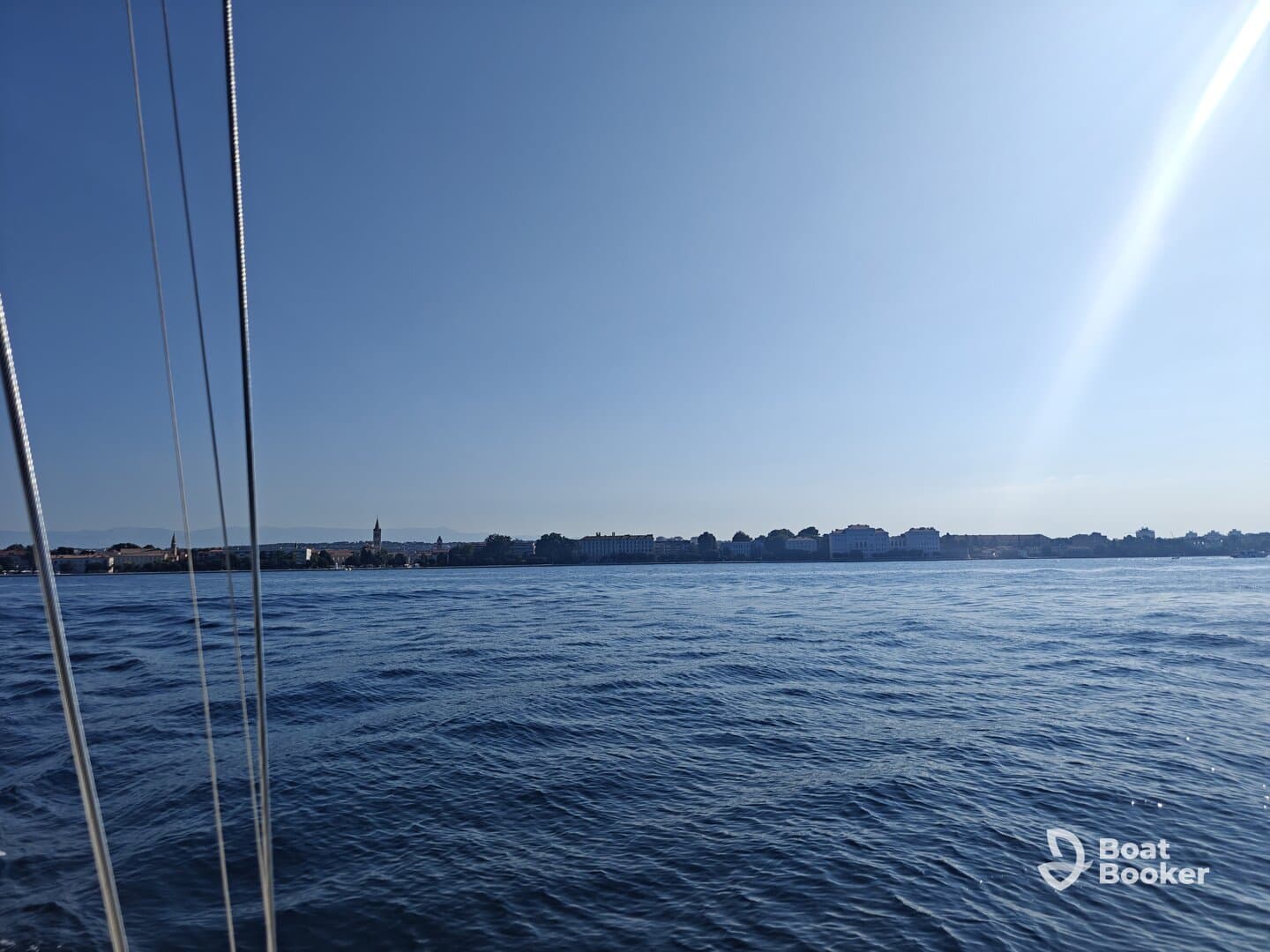 A serene view of the water with a distant shoreline, showcasing a peaceful boating experience under clear skies.