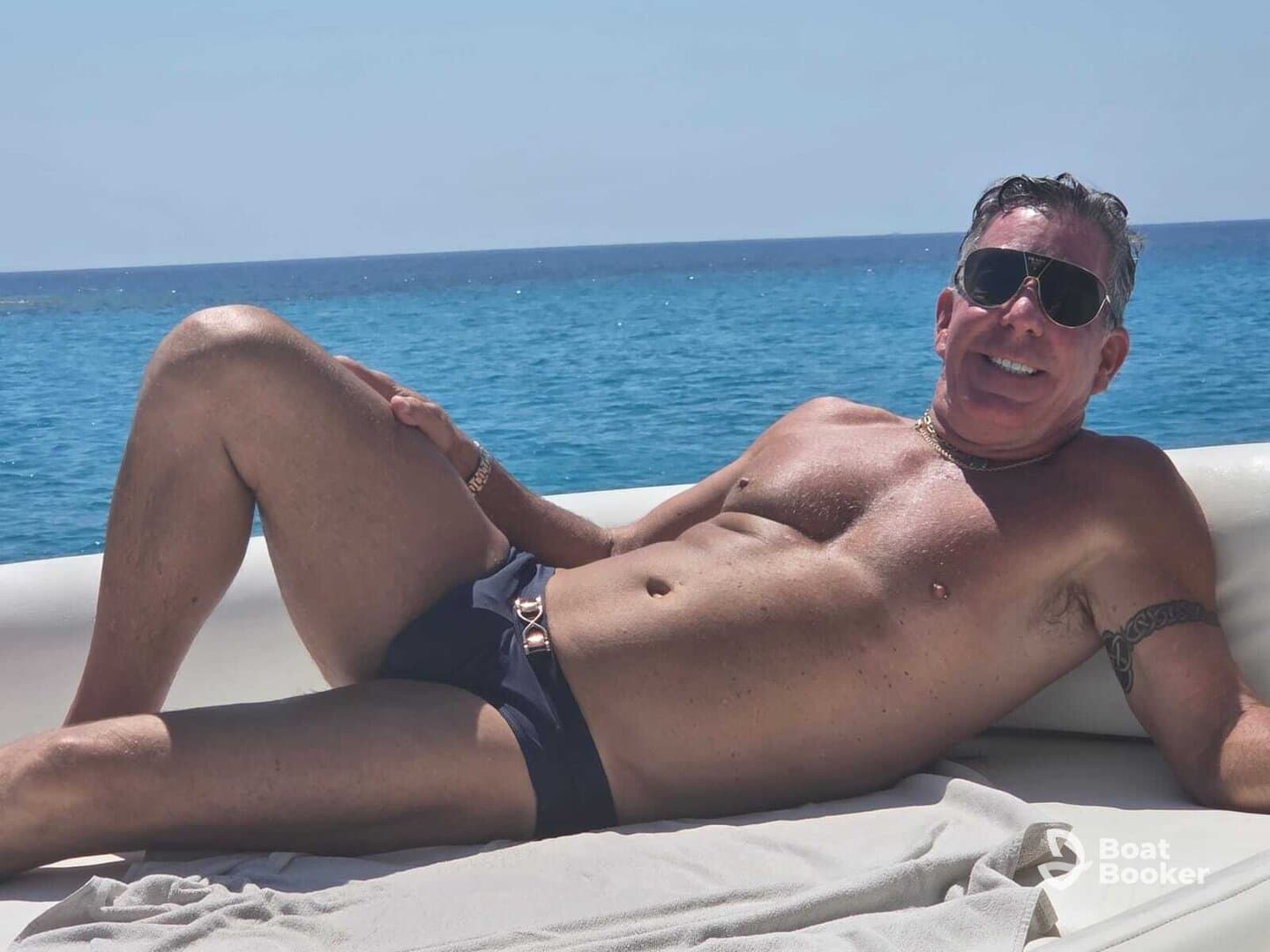 A man relaxes on a boat, enjoying the sun and ocean views — perfect for a day of leisure on the water.