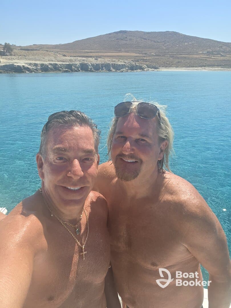 Two friends enjoy a sunny day by the ocean, capturing a fun selfie in the clear blue waters — perfect for memorable summer adventures.