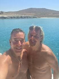 Two friends enjoy a sunny day by the ocean, capturing a fun selfie in the clear blue waters — perfect for memorable summer adventures.