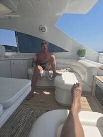 A relaxed moment inside a luxurious boat cabin, featuring a man enjoying a drink on a plush white lounge. Perfect for showcasing the comfort and style of boat interiors.