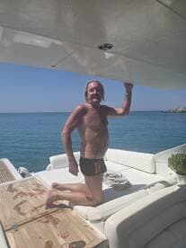 A man enjoys a moment of relaxation aboard a boat, basking in the sun with a stunning ocean backdrop — perfect for summer getaways and leisure on the water.