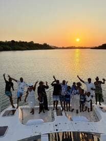 A joyful group poses on the deck of a boat at sunset, celebrating together in a picturesque setting — perfect for family gatherings or special occasions on the water.