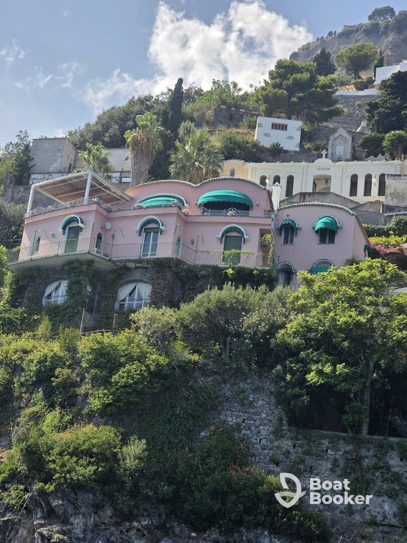 A picturesque view of a colorful villa perched on a hillside, surrounded by lush greenery and scenic landscapes.