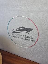 Close-up of the embroidered logo for Blue Marine Charter Amalfi Coast, showcasing the elegant branding on the boat's interior.