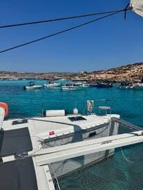 A stunning view of a catamaran docked in crystal-clear waters, surrounded by various boats, showcasing the beauty of a vibrant marine landscape.