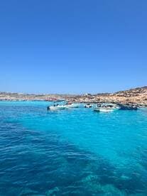 A vibrant scene showcasing multiple boats anchored in crystal-clear turquoise waters along a picturesque coastline, perfect for a day of exploration and adventure.