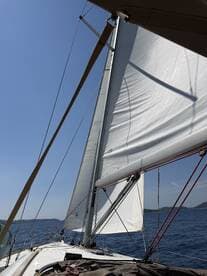 A close-up view of the sails on a sailboat, capturing the essence of sailing under clear blue skies — perfect for adventure seekers and sailing enthusiasts.