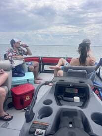 A lively group enjoys drinks aboard a pontoon boat, capturing the essence of a fun day on the water with friends.