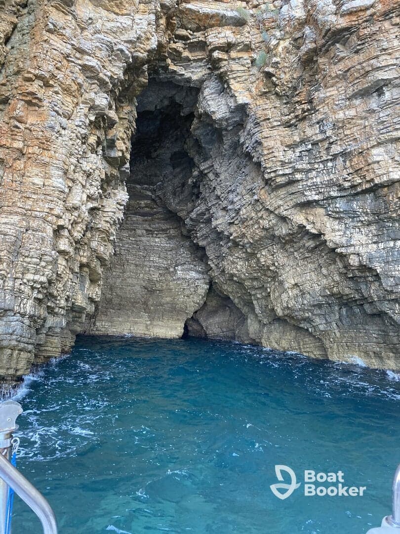 A stunning view of a rocky cave along the coastline, showcasing the natural beauty of the area — perfect for exploring hidden gems by boat.