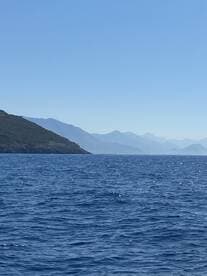 A stunning view of a serene coastline with distant mountains, capturing the beauty of the open water and perfect for nature lovers and adventure seekers.