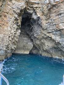 A stunning view of a rocky cave along the coastline, showcasing the natural beauty of the area — perfect for exploring hidden gems by boat.