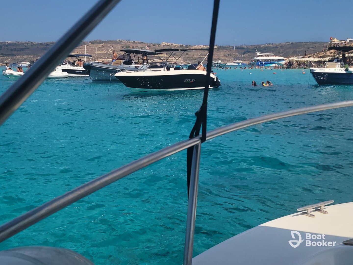 A vibrant scene of people enjoying the turquoise waters at a beach, with boats anchored nearby — perfect for a fun day out on the water.