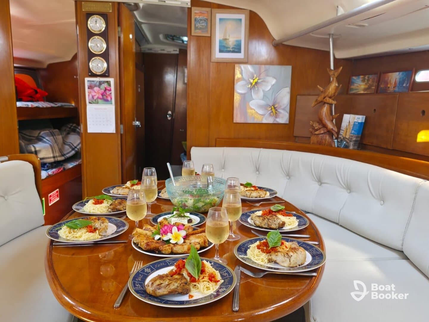 A beautifully set dining table inside a boat cabin, featuring gourmet dishes and elegant glassware, perfect for a luxurious dining experience on the water.
