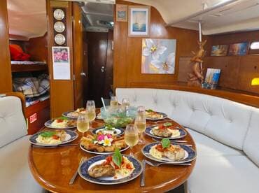 A beautifully set dining table inside a boat cabin, featuring gourmet dishes and elegant glassware, perfect for a luxurious dining experience on the water.