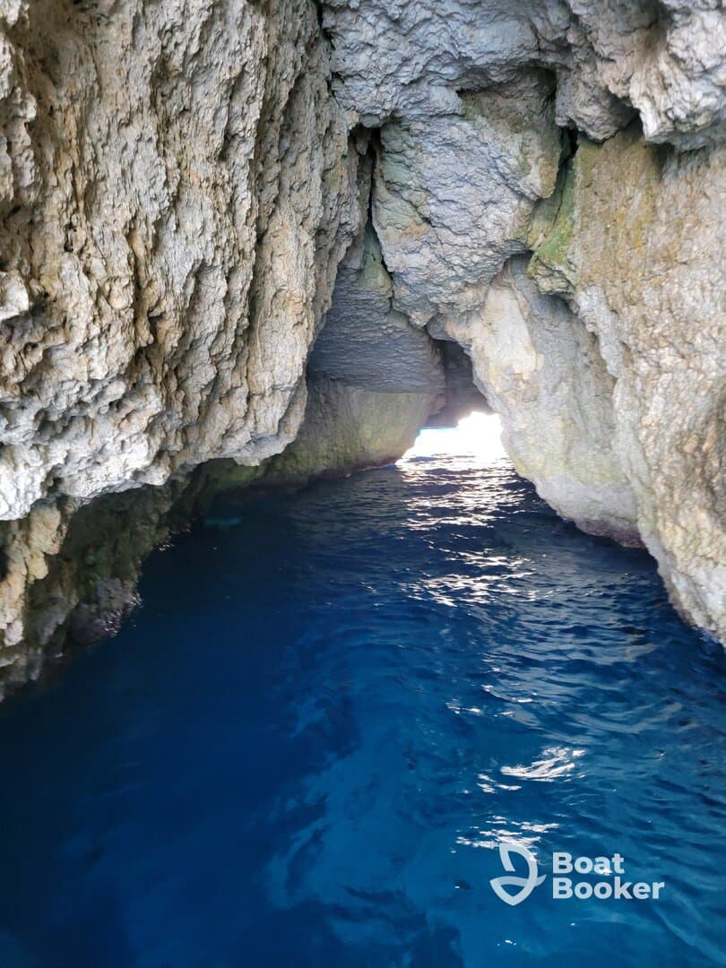 A stunning view of a cave entrance with vibrant blue water, showcasing the natural beauty of coastal landscapes — perfect for exploring hidden gems by boat.