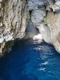 A stunning view of a cave entrance with vibrant blue water, showcasing the natural beauty of coastal landscapes — perfect for exploring hidden gems by boat.
