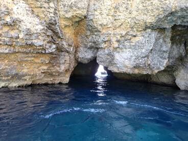 A stunning view of a cave entrance with crystal-clear waters, perfect for exploring hidden gems while boating in picturesque locations.