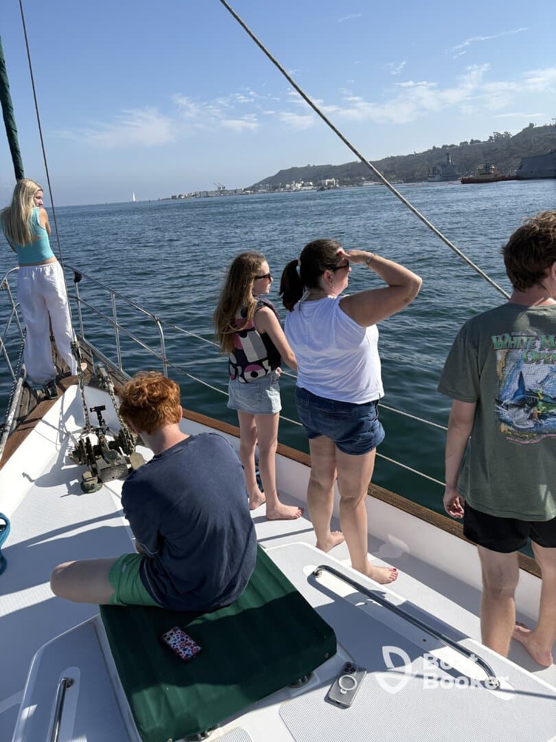 A group of friends and family enjoy a sailing trip, taking in the scenic views of the coastline while aboard a yacht.