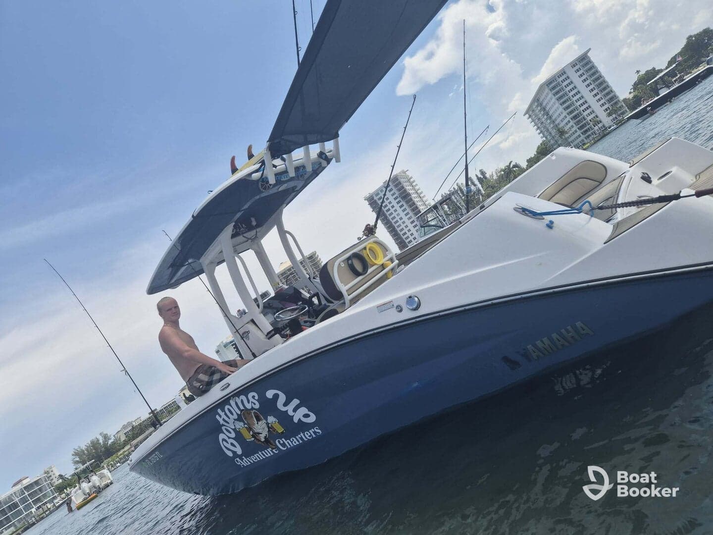 A man sits on the deck of a fishing charter boat named 'Bottoms Up,' ready for an adventure on the water. Ideal for fishing enthusiasts looking for a memorable day out.