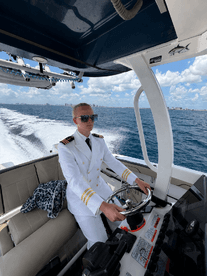 A young captain navigates the helm of a boat, showcasing the modern console and a stylish interior — perfect for those aspiring to take the helm on their next adventure.