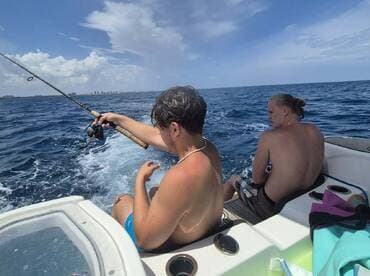 Two friends enjoy a fishing trip on a boat, casting lines into the open ocean — a perfect day for adventure and camaraderie on the water.