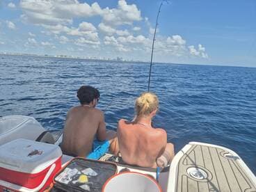 A couple enjoys a fishing trip on the open water, casting their lines into the deep blue sea — a perfect day for fishing enthusiasts.